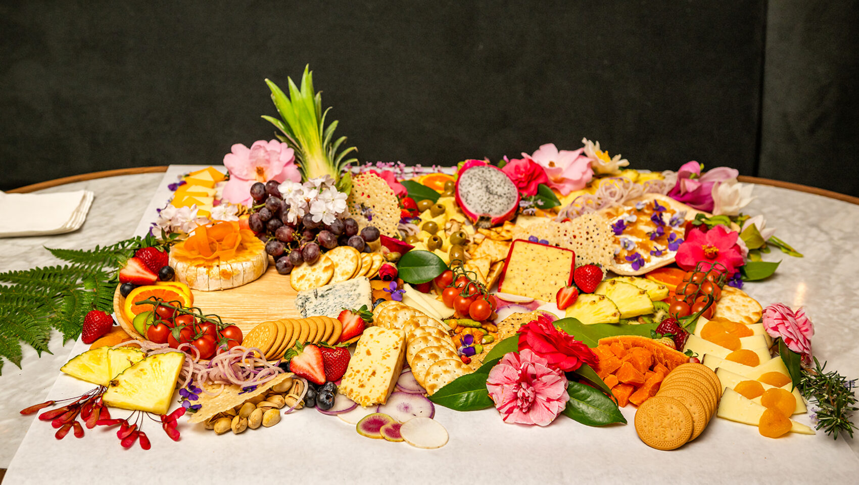 Elaborate wedding grazing board with cheeses, fruits, and floral accents
