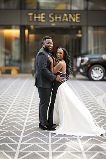 A young engaged couple, posing outside of The Shane Hotel