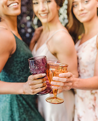 Close up of colorful party glasses, held by young women